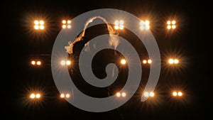 Silhouette of a girl dancing on the background of bright lights on the stage of a night club