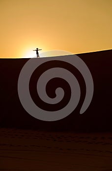 A silhouette of a girl on a desert sandune at sunrise 2