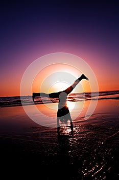 Silhouette of a girl doing a head stand in the ocean