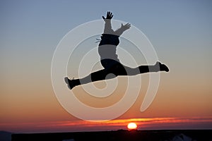 Silhouette of girl doing the splits jump in sunset photo