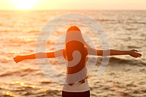 Silhouette of a girl doing yoga and mediation at sunset by the sea.