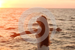 Silhouette of a girl doing yoga and mediation at sunset by the sea.