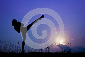 Silhouette of girl exercising side kick in the nature