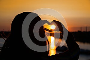 silhouette of hands forming a heart shape with sunset. expression of love and gratitude to the world.