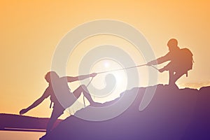 Silhouette of girl helping man teamwork success on top mountain