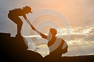 Silhouette of girl helps a boy on mountain