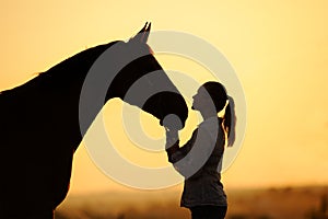 Silhouette of girl with horse at the sunset