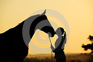 Silhouette of girl with horse at the sunset