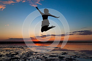 Silhouette of a girl jumping on the background of a beautiful sunset