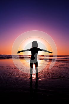 Silhouette of a girl with open arms in the ocean