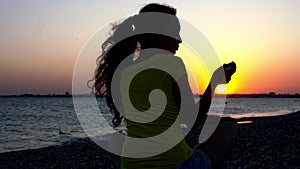 Silhouette of a girl with a phone on the beach.