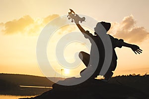 Silhouette of girl playing wooden plane in nature
