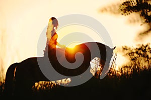 Silhouette of a girl riding a horse at the sunset photo