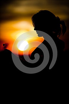 Silhouette of girl`s face holding cloverleaf during sunset - Black and orange colors