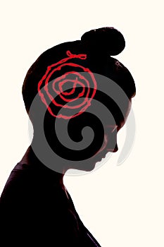 A silhouette of a girl`s head, with a red rope with knots on it as a keepsake photo