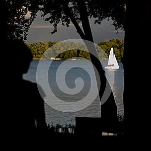 Silhouette of a girl and a sailboat on the river.
