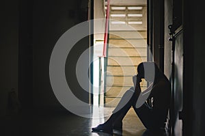 Silhouette of girl sitting alone,Sad and Serious women sitting hug his knee alone of close condo., Dramatic moment. with copy