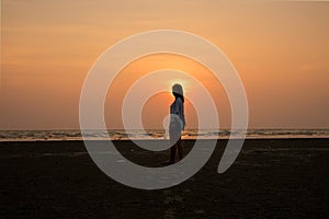 Silhouette girl standing on beach and sunset.