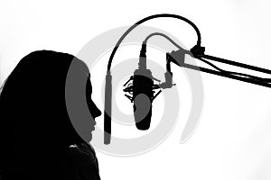 Silhouette of a girl with a studio microphone, radio presenter, singer and blogger, voice acting for films. Strong, black and