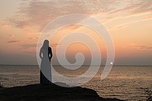 Silhouette of a girl on a sunset background sunrise on the sea