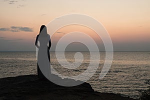 Silhouette of a girl on a sunset background sunrise on the sea