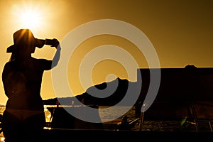 Silhouette of girl taking pictures with mobile phone. With sunset.