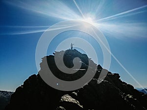 Silhouette of a girl on top of of the Penalara mountain in Spain with the sun shining in the sky photo