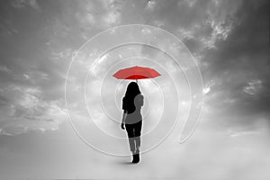 Silhouette of girl with umbrella in a dreamlike context - red umbrella with leaden sky -