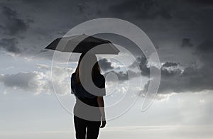 Silhouette of girl with umbrella in a dreamlike context - red umbrella with leaden sky