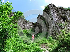 Silhouette of girl walking down the path among high stone walls of a medieval castle in Khust, Ukraine