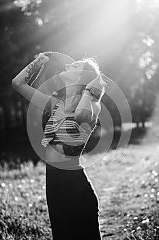 Silhouette of girl walking in park outdoor. Sunny summer lifestyle concept. Woman in dress and hat in field with