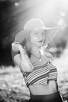 Silhouette of girl walking in park outdoor. Sunny summer lifestyle concept. Woman in dress and hat in field with