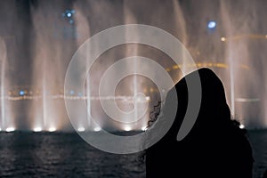 Silhouette of a girl watching the dancing fountain in Dubai