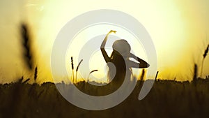 Silhouette of girl watching sunset in wheat field