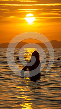 Silhouette of a girl in the water during a virant orange sunset in the sea, in Ao Nang, Thailand