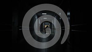 Silhouette of a girl on a wheelchair in a dark corridor.