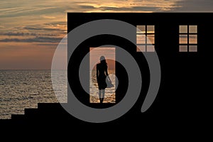 Silhouette of a girl in windowed openings of an old house ruins