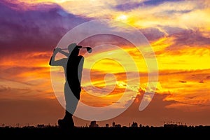 Silhouette golfer hit sweeping on sunset background. Golfer young man playing golf during beautiful sunrise sky with city