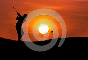 Silhouette golfer hitting golf ball at sunset