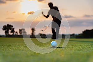 Silhouette golfer showing happiness when win in game , white golf ball on green grass of golf course