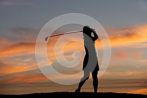 Silhouette of golfer swinging.