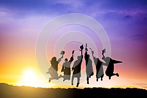 The Silhouette of  graduation group celebrating and jumping on mountain