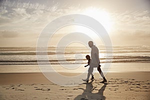 Silhouette Of Grandfather Walking Along Beach With Grandson photo