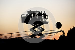 Silhouette of group of cameramen on the lift at a summer event