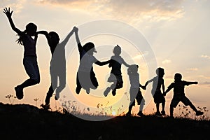 Silhouette, il gruppo di bambini felici di giocare sul prato, tramonto, periodo estivo.