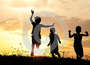 Silhouette, il gruppo di bambini felici di giocare sul prato, tramonto, periodo estivo.