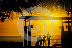 Silhouette, a group of happy children, admiring the beautiful yellow sea sunset. palm leaves. hotel in Thailand. summer.