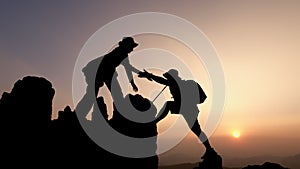 Silhouette of group team tourists lends helping hand climb cliffs mountains helping hand. teamwork helping hand business travel