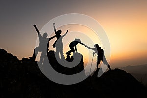 Silhouette of Group team tourists lends helping hand climb cliffs mountains helping hand. teamwork people climbers climb top