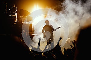 Silhouette of guitar player, guitarist perform on concert stage. Dark background, smoke, concert spotlights